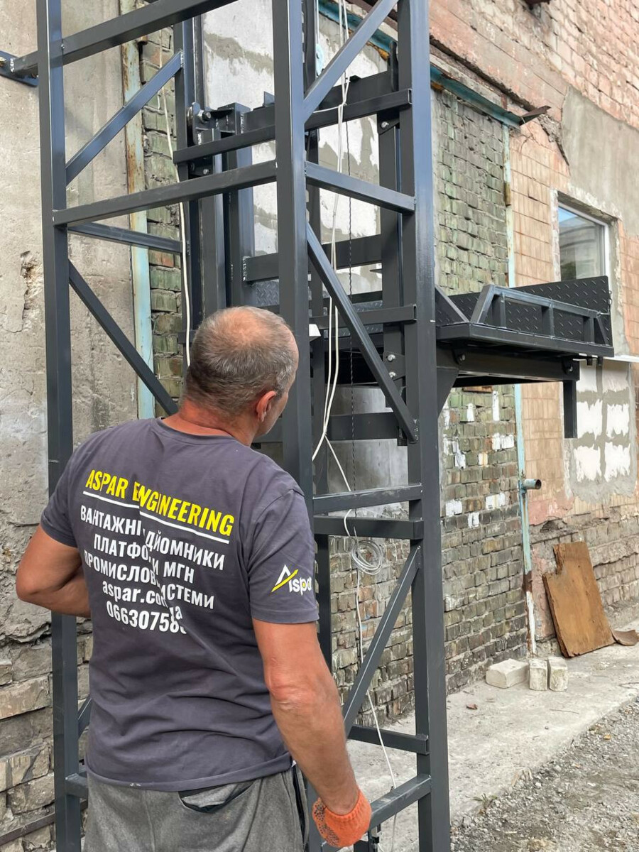 ASPAR worker beside a steel lift structure and platform on site