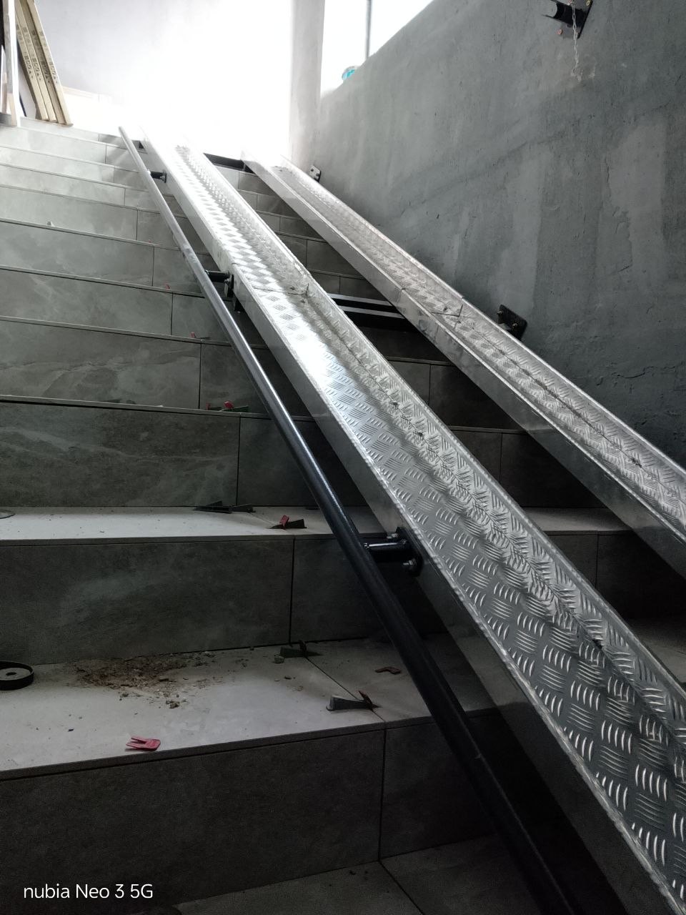 Aluminium rails of a fold-down ramp on a stair flight