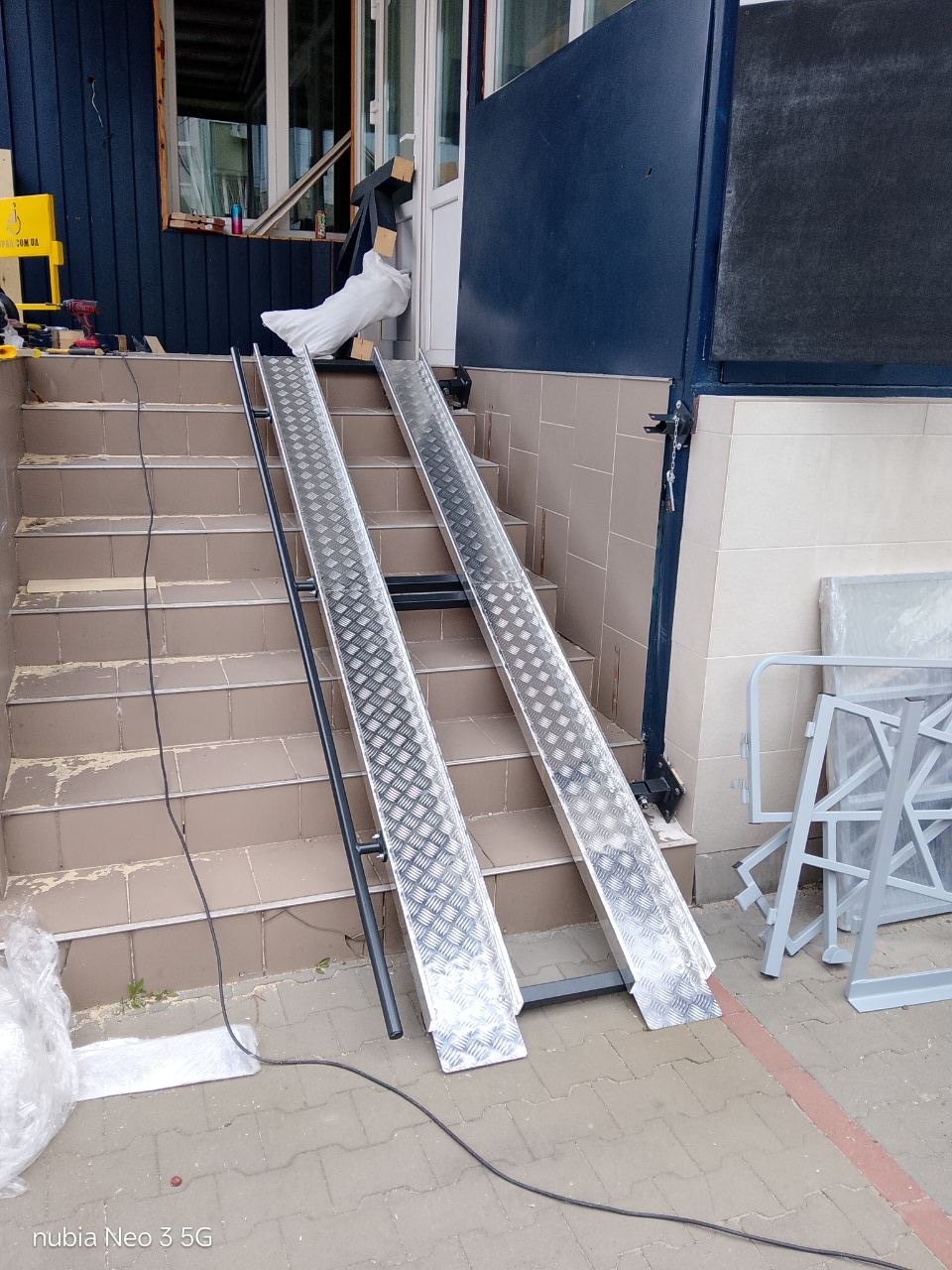 Outdoor fold-down aluminium ramp at a building entrance