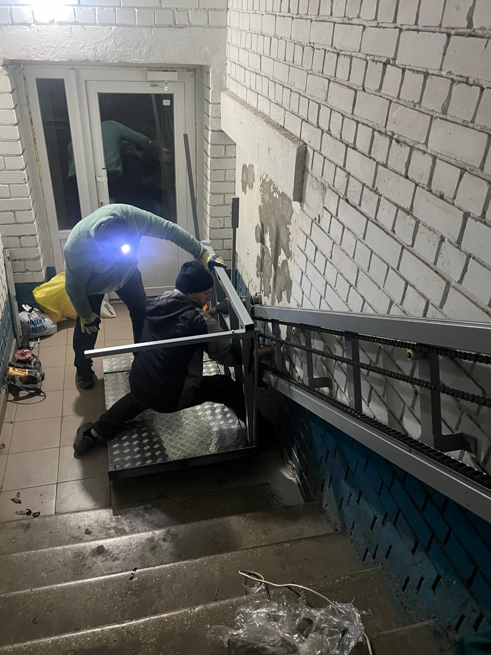 Команда встановлює похилий підйомник у під’їзді